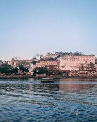 River by buildings against clear sky