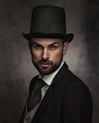 Portrait of man wearing hat against black background