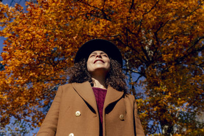 Portrait of smiling young woman in autumn tree