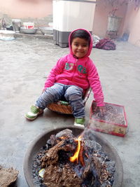 Portrait of smiling indian baby girl, burning fire in winter season