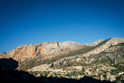 Low angle view of mountains against clear blue sky