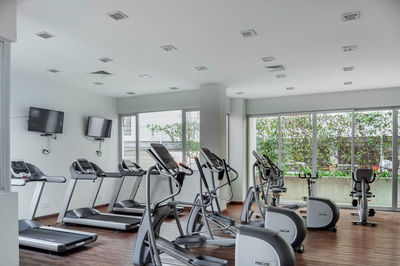 Gym as an amenity within apartment towers, treadmill with televisions, exercise and ecliptic bikes