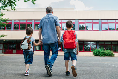 Back to school. view from the back of a happy dad escorts his sons schoolchildren to school.