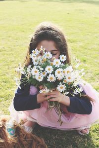 Full length of girl with flowers on field