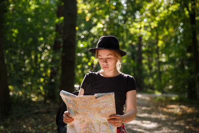 Side view of young man standing in forest