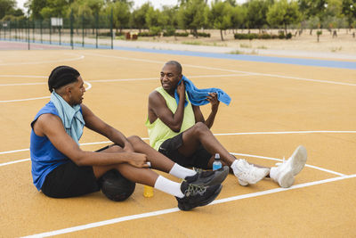 Father and son taking break sitting at basketball court