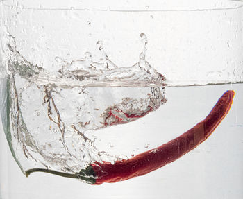 Close-up of water splashing on glass against white background