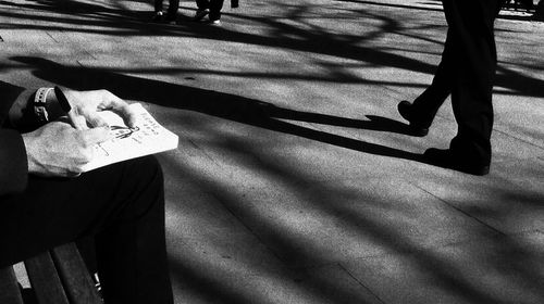 Low section of man writing in book on sunny day