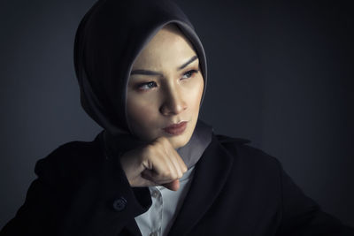 Portrait of woman against black background