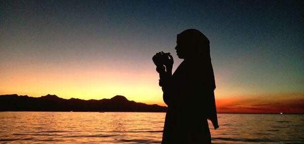 Women standing by the sea enjoying the breeze at sunset