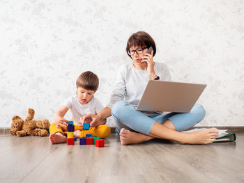 Mother talking on phone while helping son at home