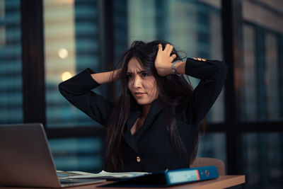 Frustrated businesswoman with hand in hair sitting at desk