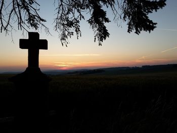 Silhouette cross against sky during sunset