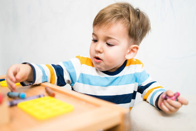 Cute boy holding crayons at home