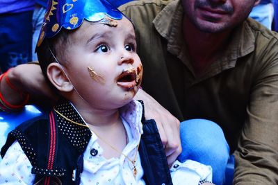 Close-up of surprised messy boy wearing party hat during birthday party