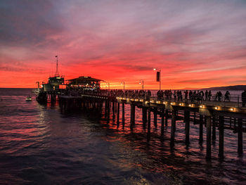 Pier over sea against orange sky