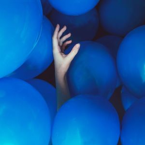 Cropped hand amidst blue balloons