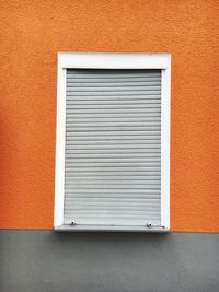 Closed white window on orange wall