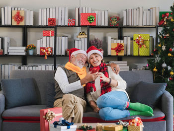 Portrait of young woman using mobile phone while sitting on sofa at home