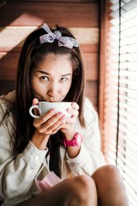 Portrait of woman drinking coffee while sitting at home