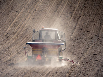 Arable field being planted by farm tractor with sowing machine