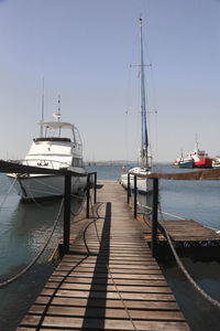 Boats moored at harbor against clear sky