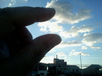 Low angle view of cropped hand against sky