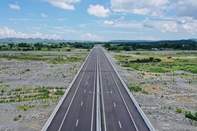 Road amidst field against sky