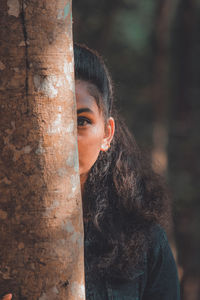 Portrait of woman with tree trunk in forest