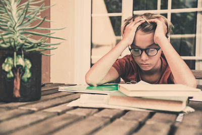 Frustrated boy siting next to books on desk at home