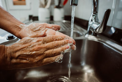 Cropped image of man washing hands in sink