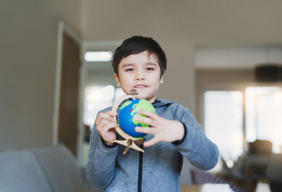 Portrait of boy holding ball at home