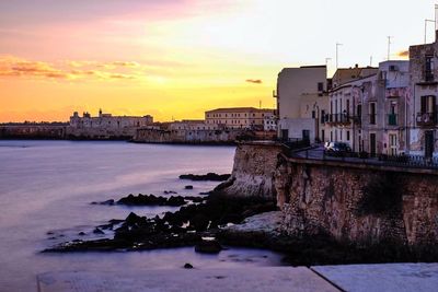 View of city at waterfront during sunset