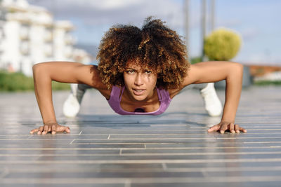 Portrait of young woman doing push-ups at footpath