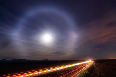 A bright moon halo shines in the night sky as traffic flows along interstate 10 in tucson, arizona