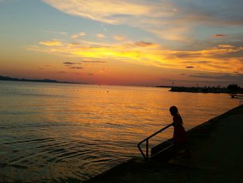 Silhouette girl on pier against sky during sunset
