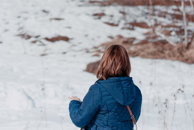 Rear view of woman standing on snow covered field during winter