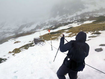 Rear view of man hiking on snowcapped mountain