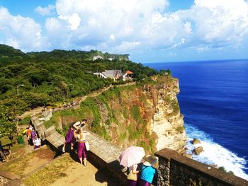 People on cliff by sea against sky