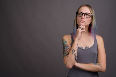 Portrait of beautiful young woman standing against wall