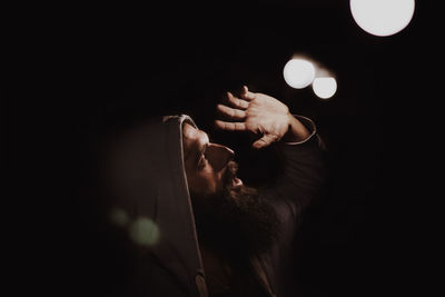 Mature man looking at illuminated lights against sky at night