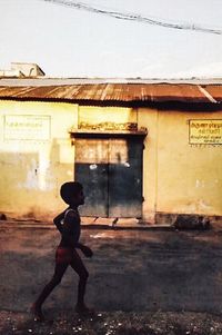 Side view of boy standing against building