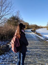 Rear view of woman standing on footpath against sky