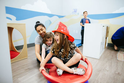 Girl wearing a fireman hat smiles as she is spun on a sensory seat