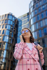 Portrait of young man standing against modern buildings