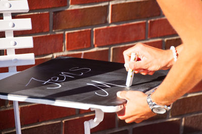 Cropped image of person writing on slate