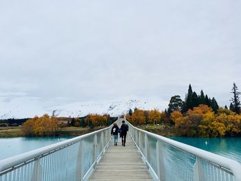 Rear view of people walking on footbridge