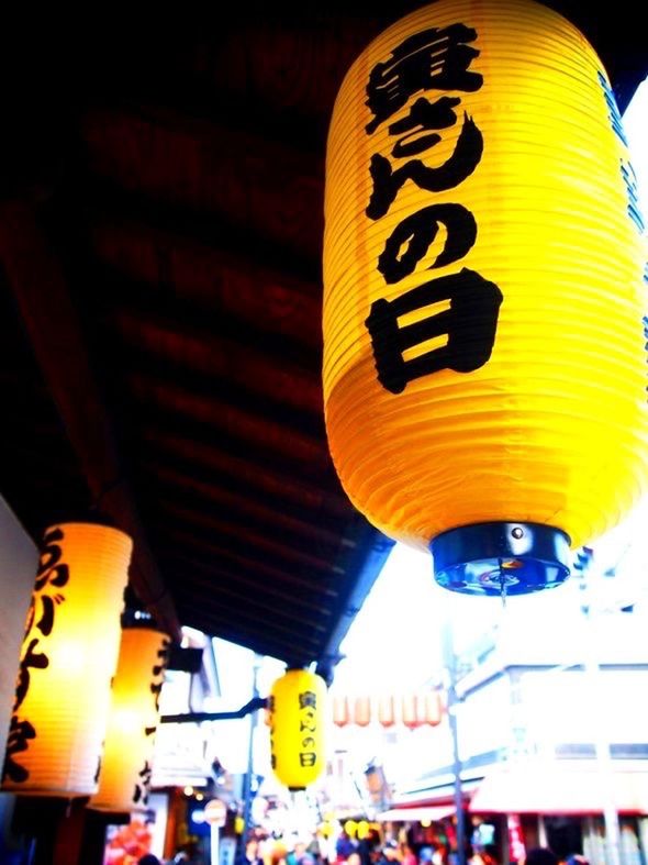 yellow, low angle view, illuminated, text, architecture, built structure, building exterior, communication, lighting equipment, city, western script, hanging, outdoors, non-western script, transportation, sign, information sign, sky, incidental people, city life