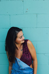 Beautiful woman looking away while leaning on wall