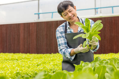 Portrait of smiling woman standing by plants